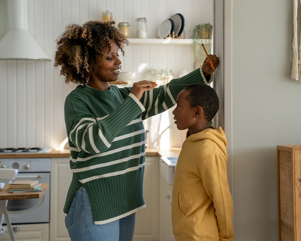mother measuring sons height on the wall