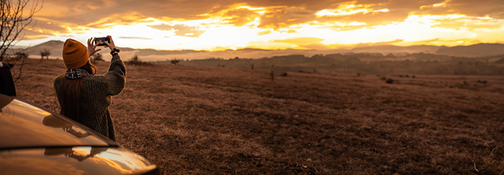 woman taking picture of land at sunset