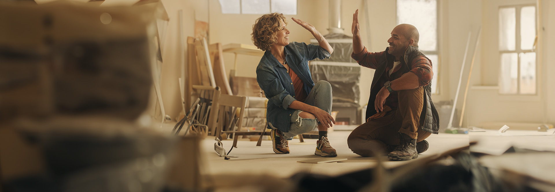 middle aged couple high fiving in home remodel