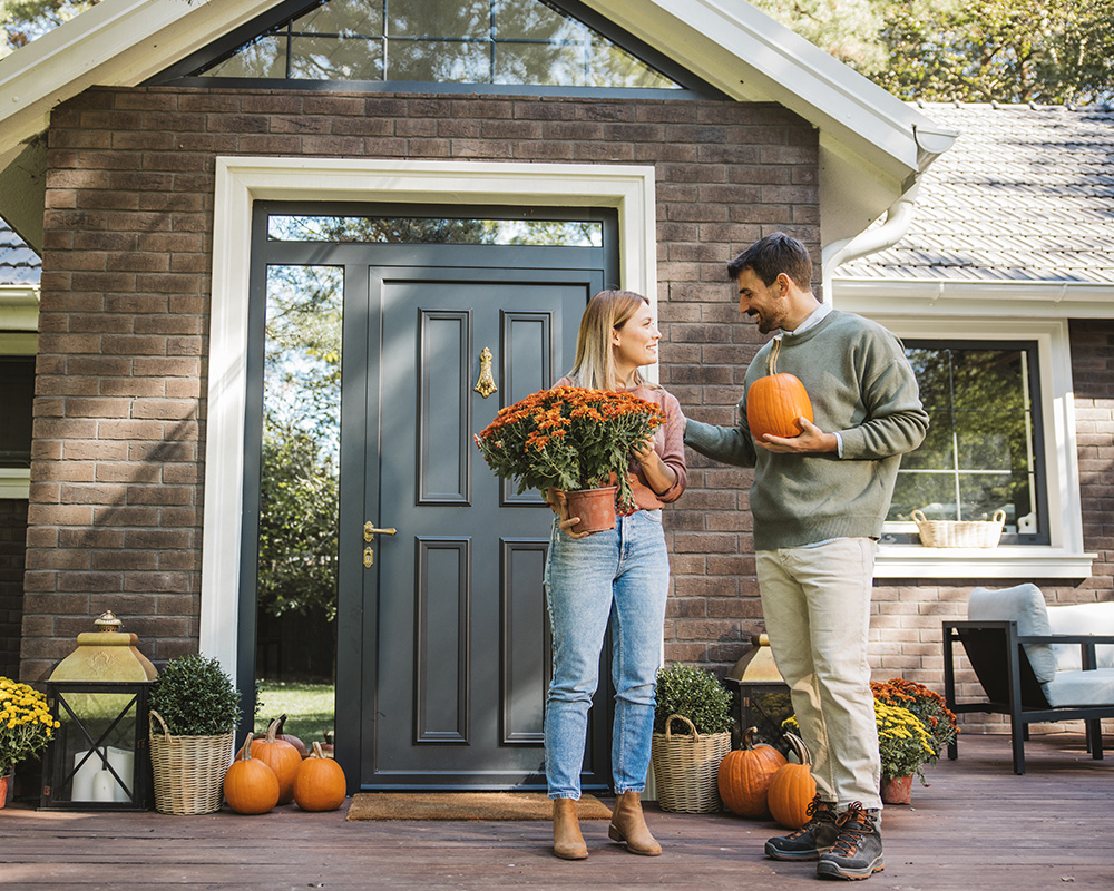 couple putting pumpkins on their porch