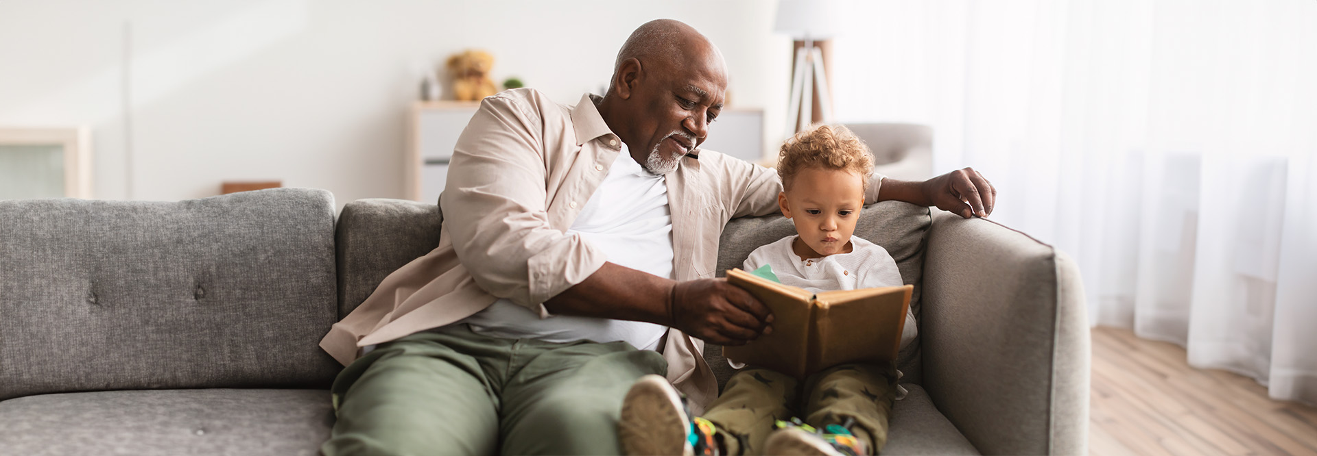 grandpa reading to his young grandson on the couch