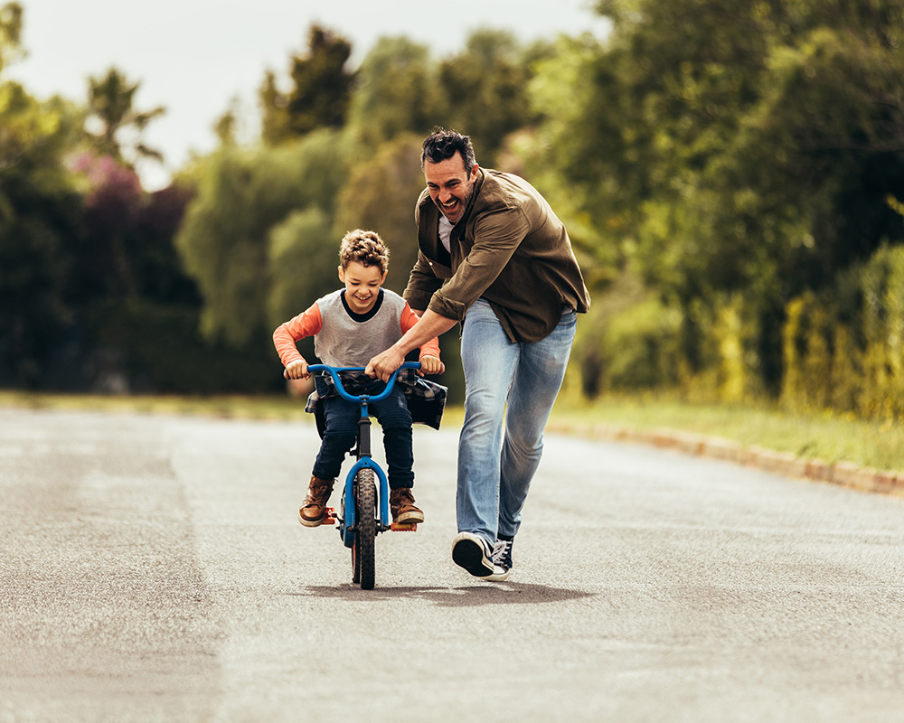 father teaching son to ride a bike 