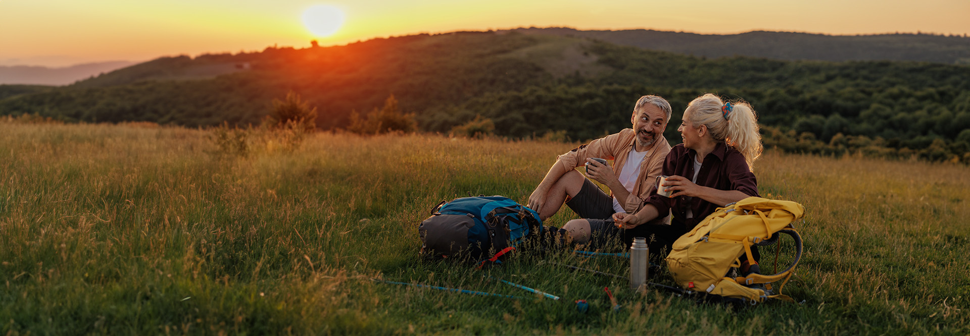 middle aged couple sitting at the foot of a mountain after hiking