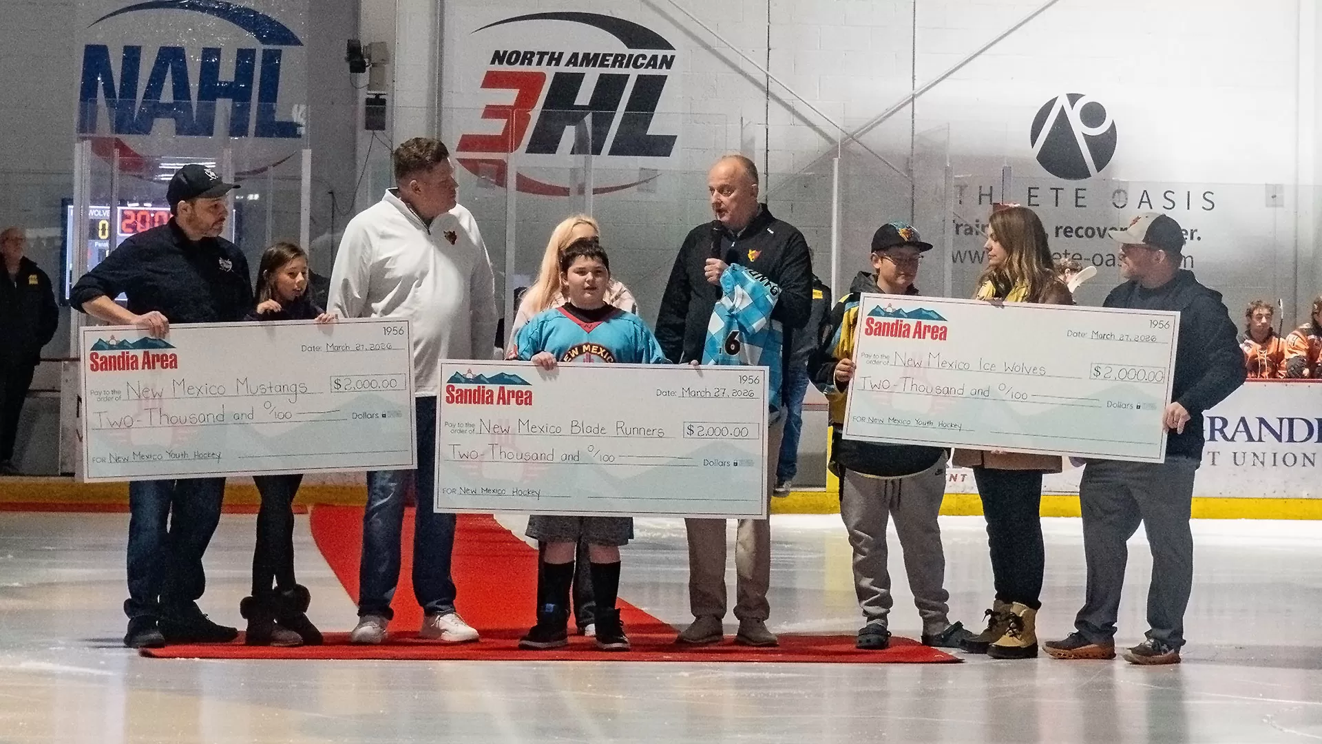 Kevin Todd, CEO of Sandia Area FCU, presents 3 large checks to the NM Ice Wolves