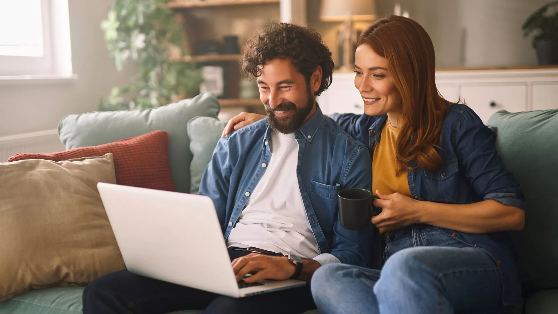 happy couple on laptop sitting on couch