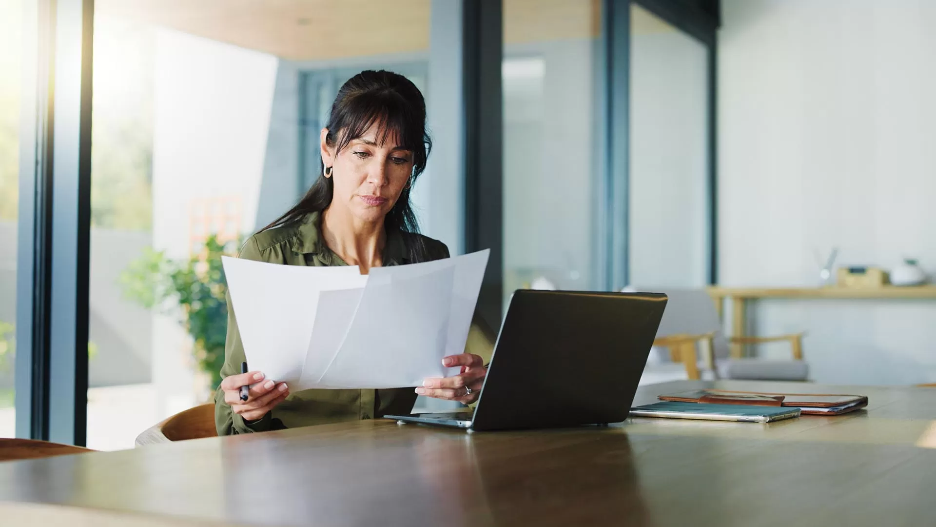 Woman looking at papers in front of laptop