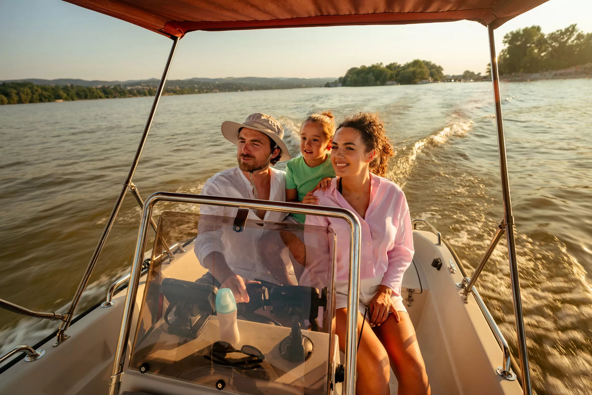 family on a driving a boat on a lake at dusk